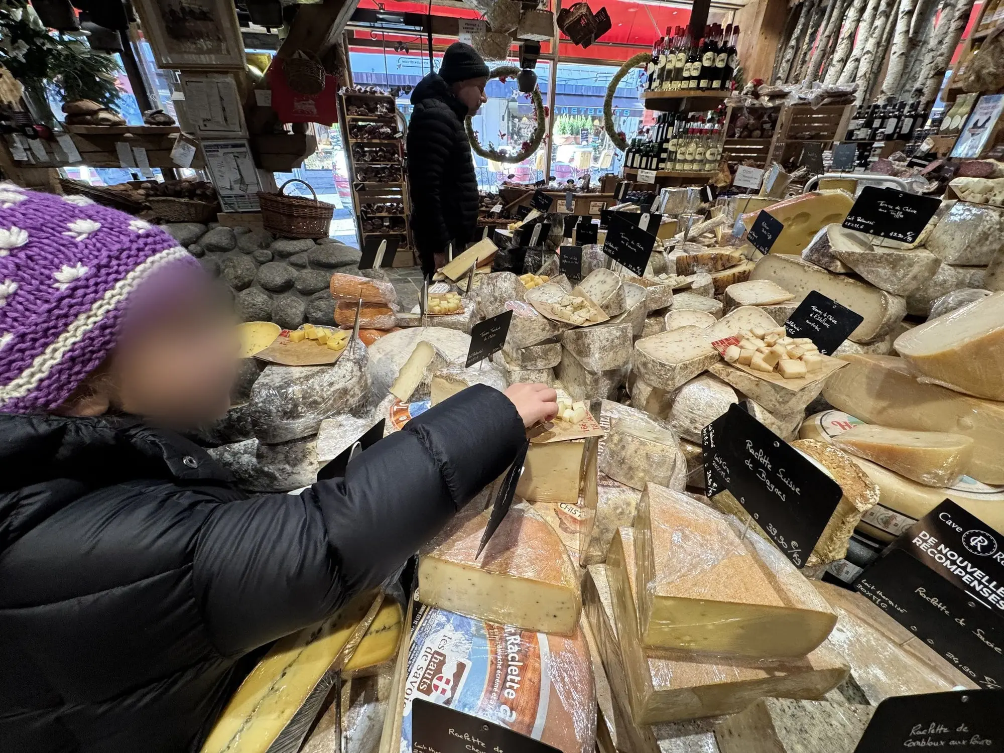 Une enfant goûte les fromages dans une fromagerie de Chamonix