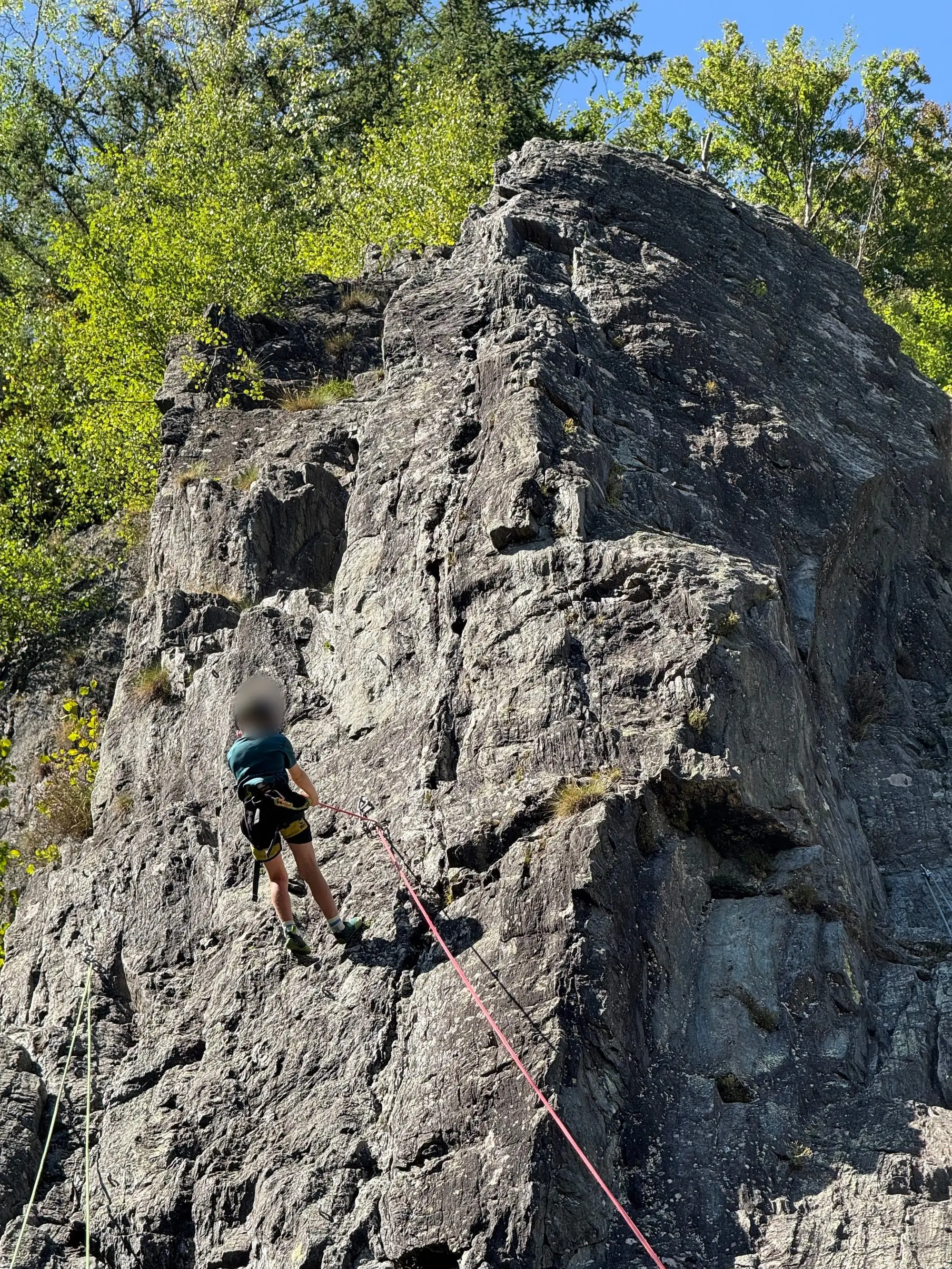 Un grimpeur au pied d'un gros bloc de rocher, en forêt