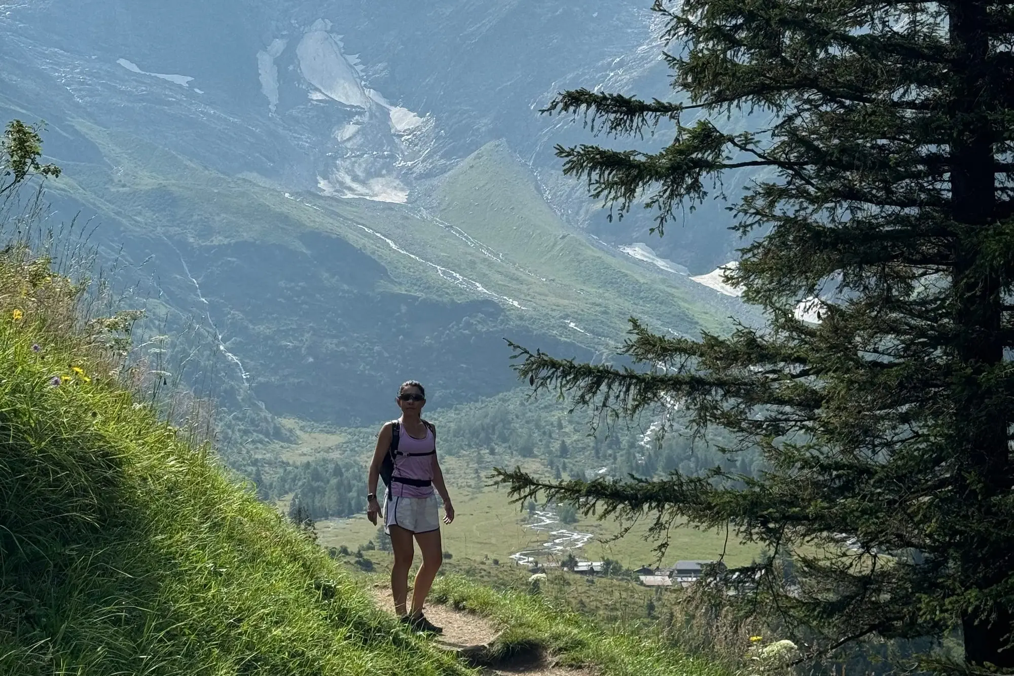 Un randonneur sur un sentier de montagne, sommets enneigés en face