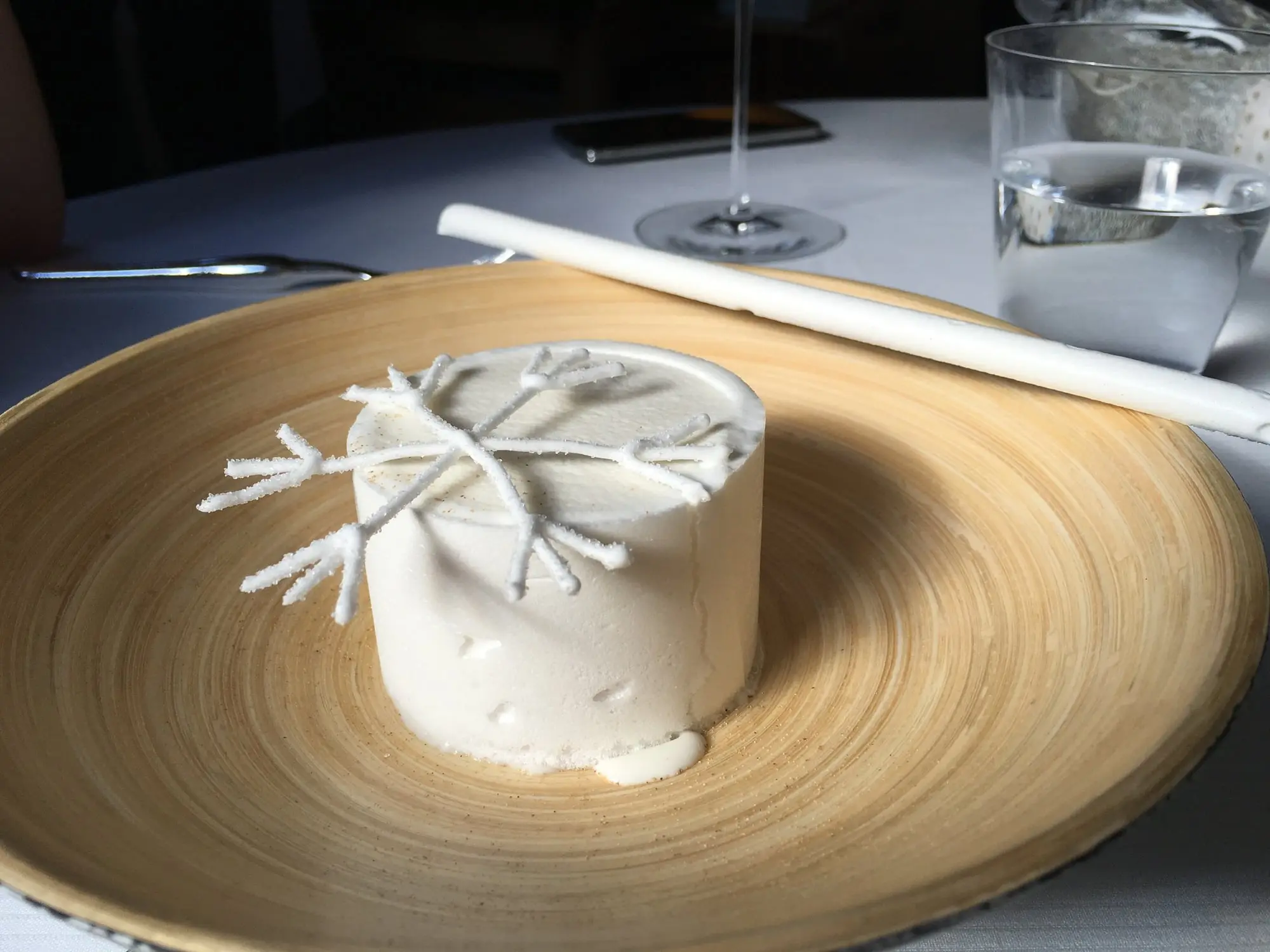 Un dessert blanc décoré d'un flocon, dans une assiette en bois