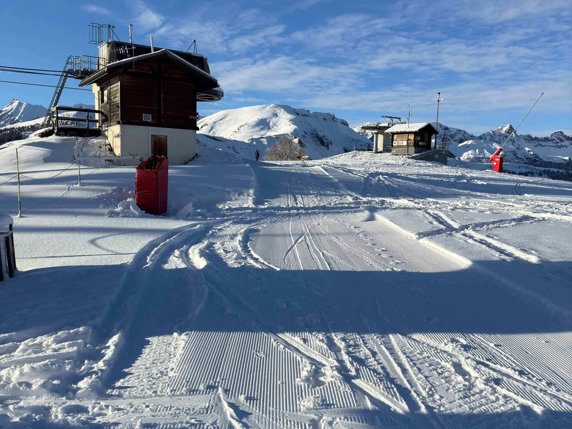 Une piste damée et un chalet d'altitude