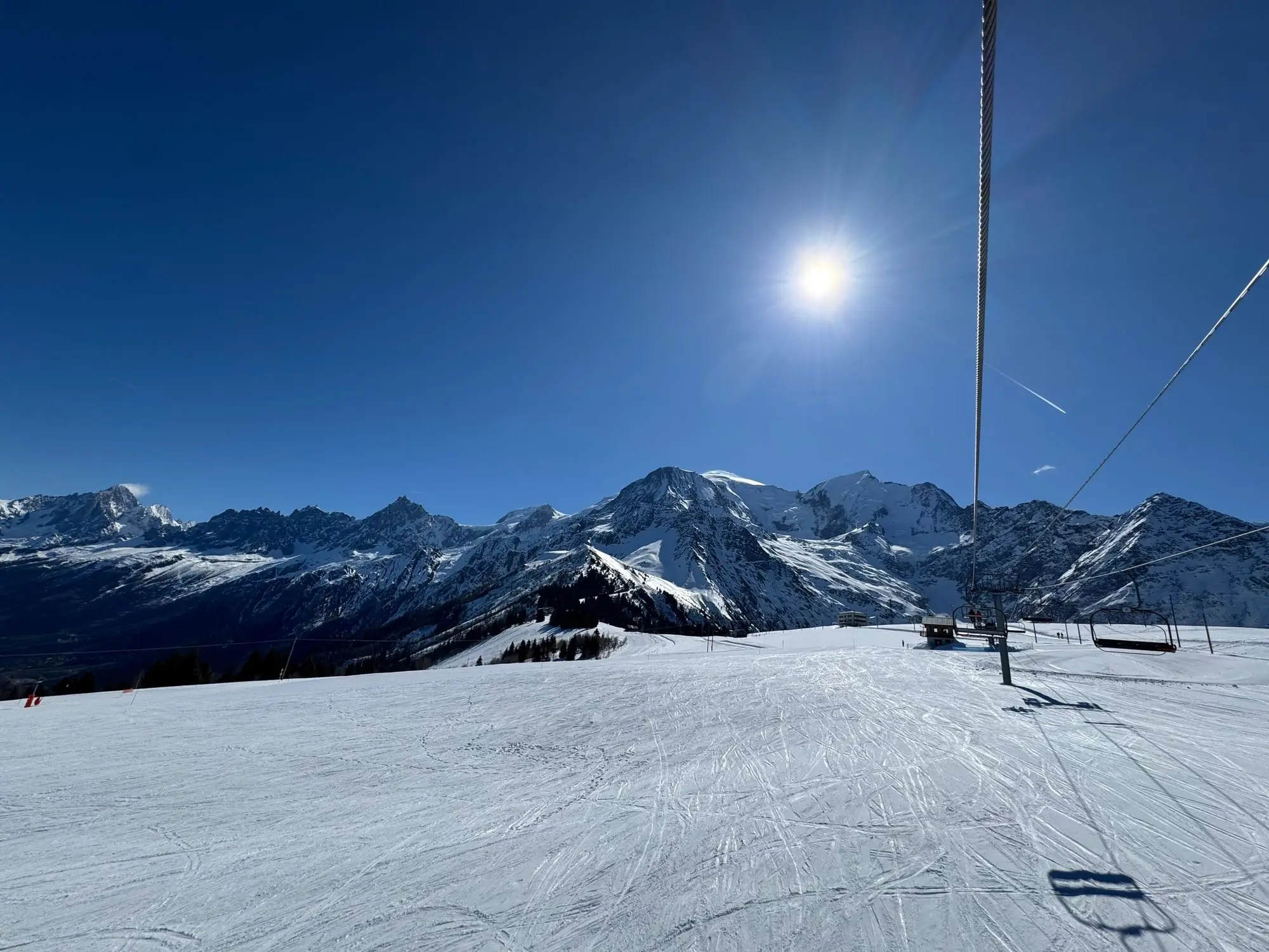 Une piste damée au soleil, les sommets en face