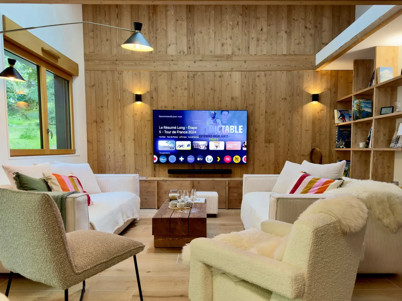 Le coin salon devant le mur en bois, écran et étagères