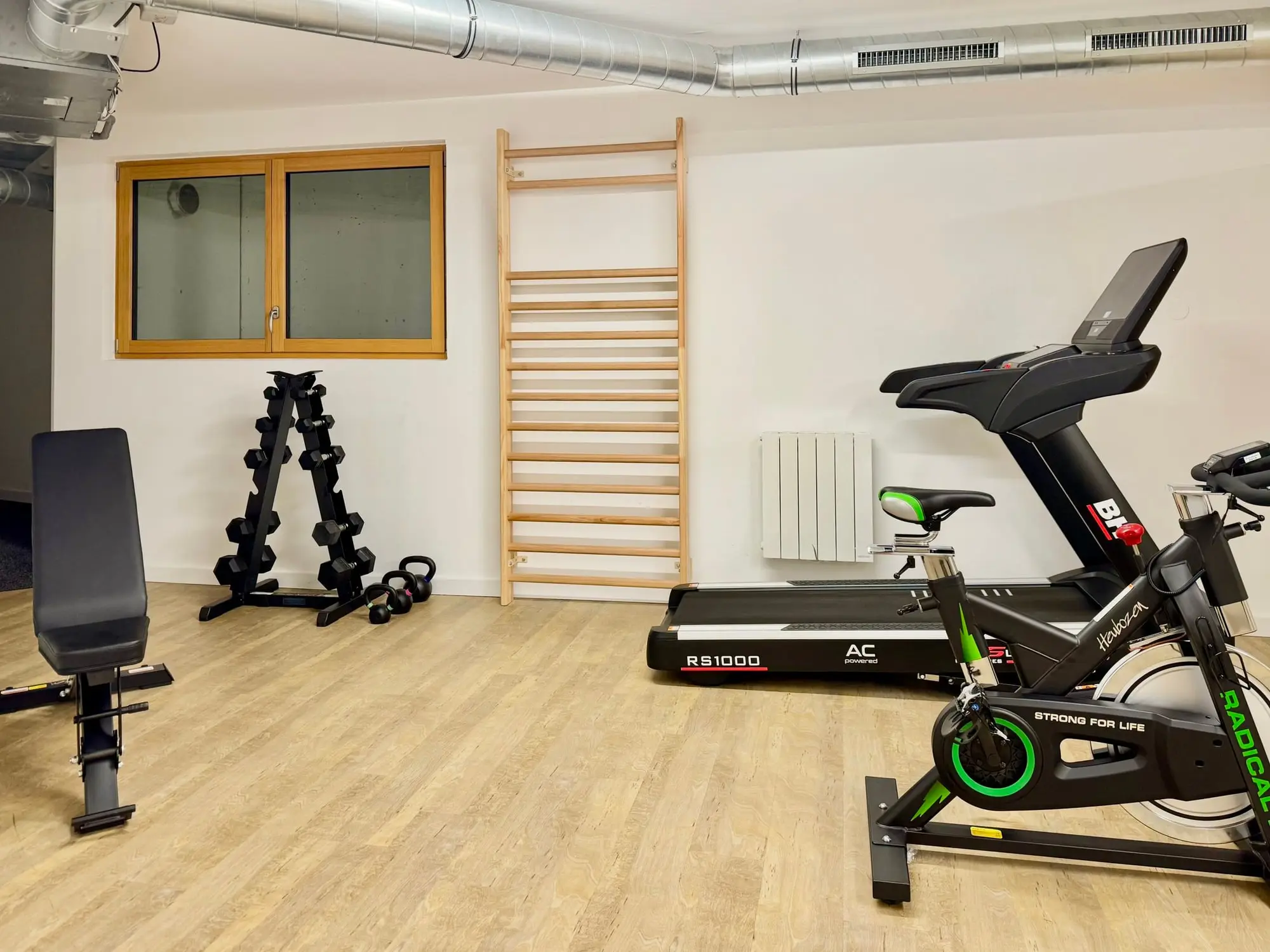 La salle de sport : vélo, banc de musculation et haltères