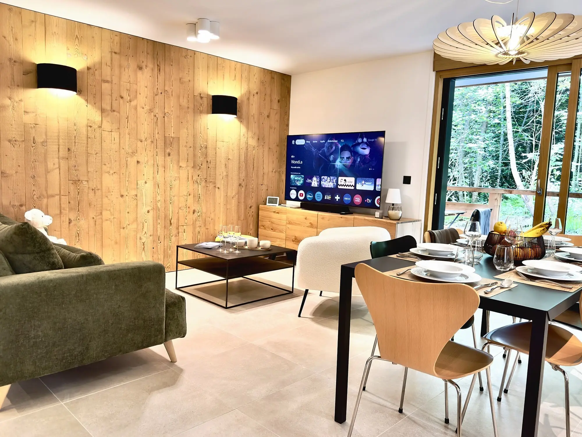 La pièce de vie du T3 : salon, table dressée et cuisine, ouverts sur la forêt