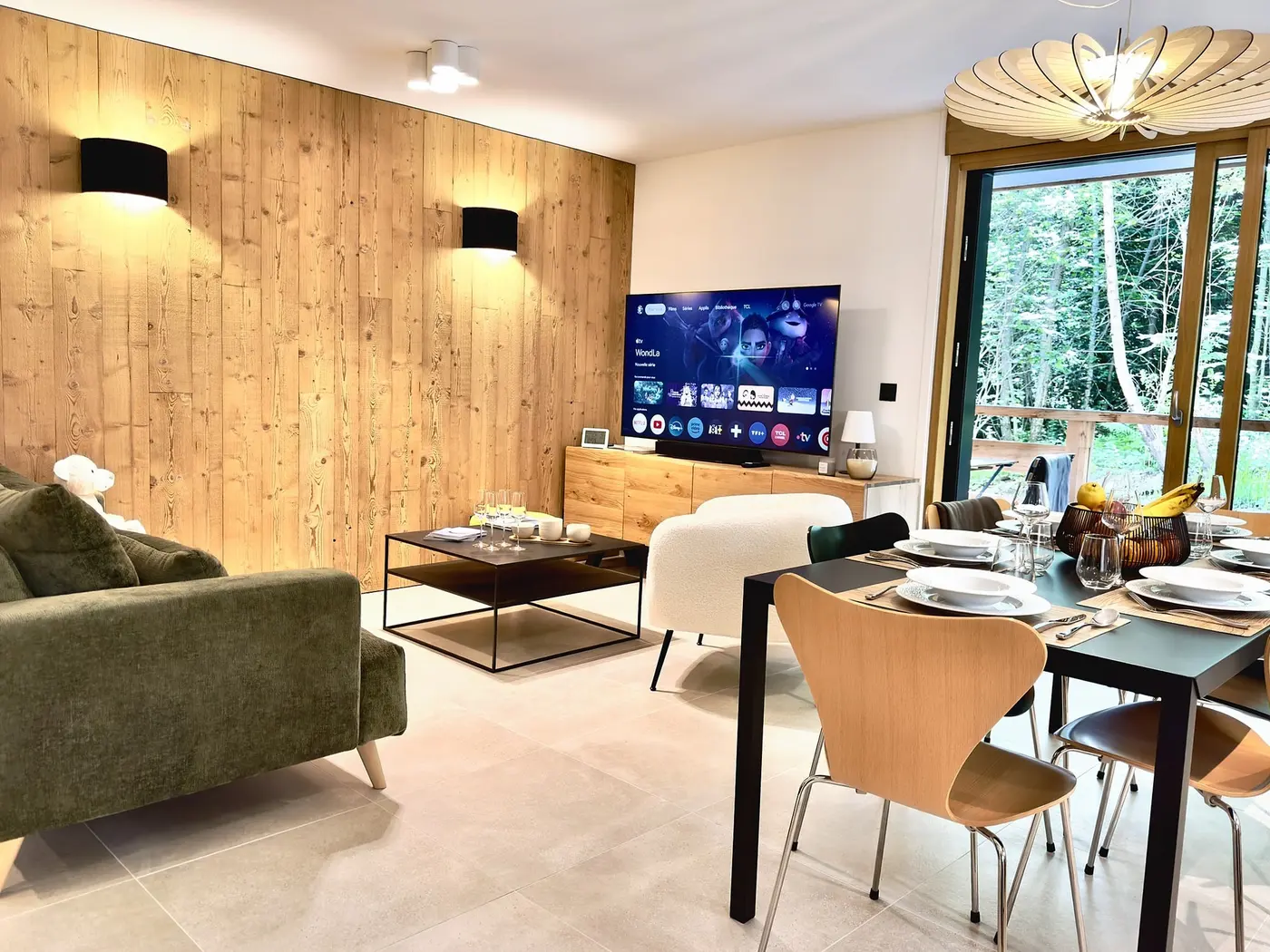 La pièce de vie du T3 : salon, table dressée et cuisine, ouverts sur la forêt