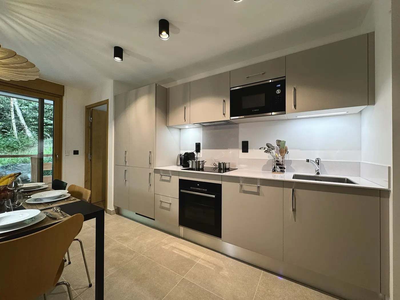 La cuisine vue depuis la table, la baie vitrée au fond